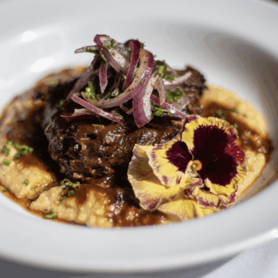 Braised short rib with polenta and garnish.