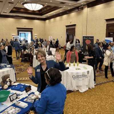 Woman waves at business expo crowd.