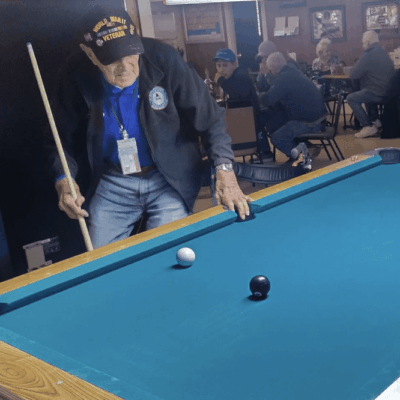 Veteran playing pool, aiming shot.