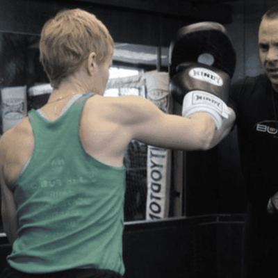 Woman boxing with trainer at gym.