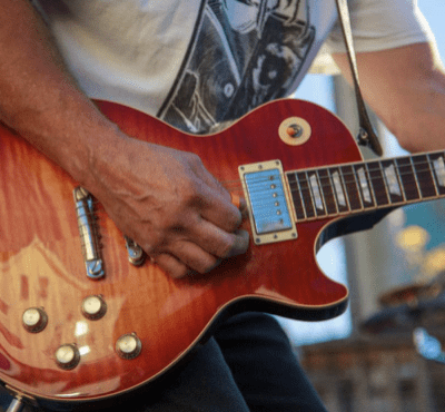 Person playing a red electric guitar.