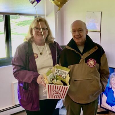 Man and woman celebrating with balloons and snacks.