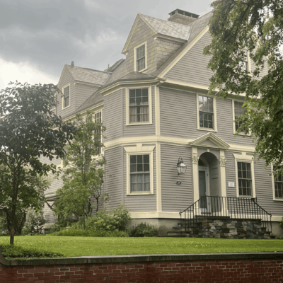 Gray house with stone steps and trees.