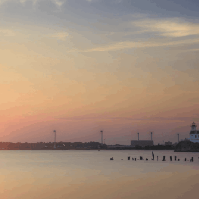 Sunset over lighthouse and calm water.