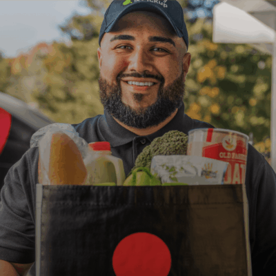 Smiling delivery driver holding grocery bag.