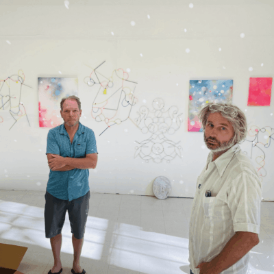 Two artists in art studio with paintings.