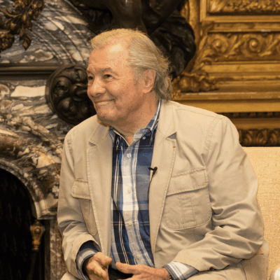 Smiling older man in tan jacket.