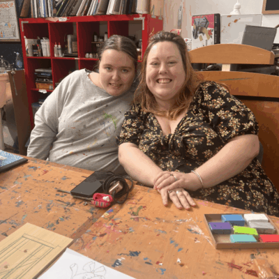 Two women smiling at an art table.