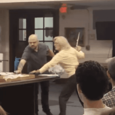 Woman fights man with stick at meeting.