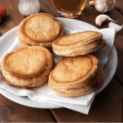 Four golden-brown savory pastries on plate.