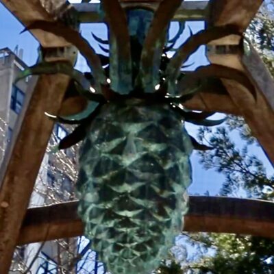 Bronze pine cone sculpture outdoors.