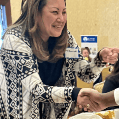 Woman in patterned cardigan shaking hands.