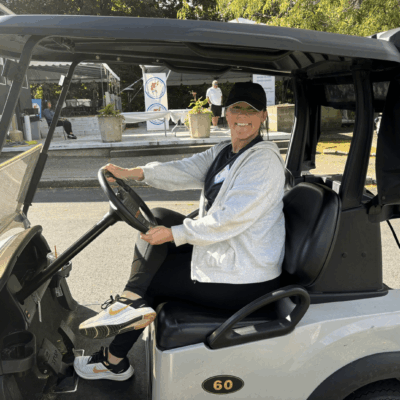 Woman smiling, driving golf cart.