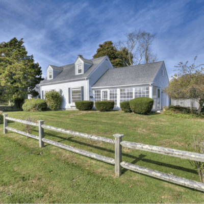 White house with sunroom and fence.