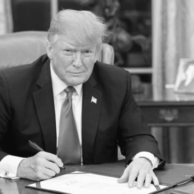 Black and white photo of Donald Trump signing.
