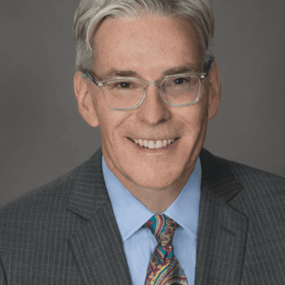 A man in a suit and tie smiling for the camera.