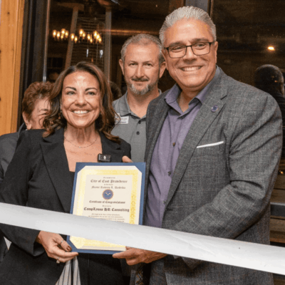 A group of people standing around a ribbon cutting.