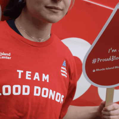 A person holding up a red sign with blood donors on it.