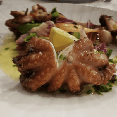 A plate of food with octopus and lemon on it.