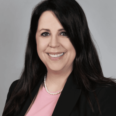 A woman in black jacket and pink shirt.