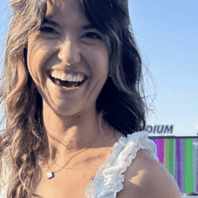 A woman smiling for the camera with her hair in front of a building.