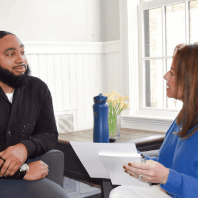 A man and woman are sitting in chairs talking.