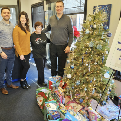 A group of people standing around a christmas tree.