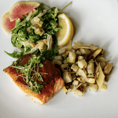 A plate of food with salmon, potatoes and salad.