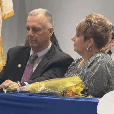 A man and woman sitting at a table with flowers.