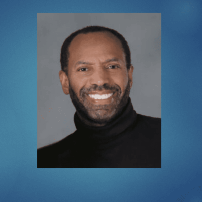 A man with a beard and black shirt smiling.