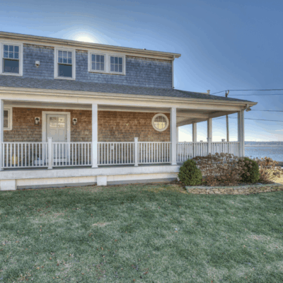 A house with grass and a clock on the front porch.
