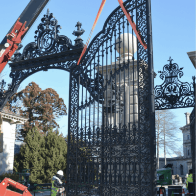 A crane is lifting the iron gate into place.