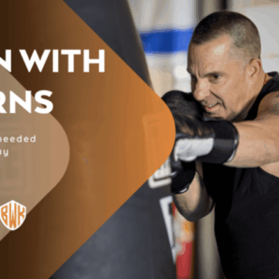 A man is boxing in the gym with his arms out.