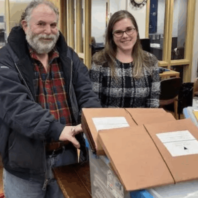 Two people standing beside a box.