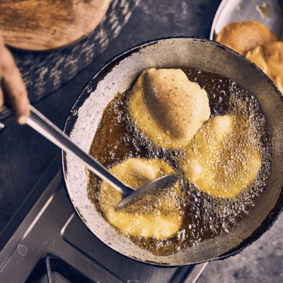 Frying puris in hot oil on stove.