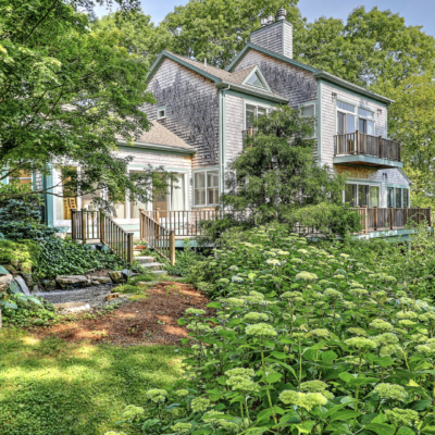 Two-story house surrounded by lush greenery.