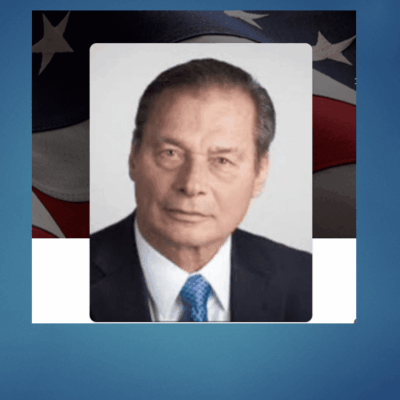 Man in suit with American flag background.