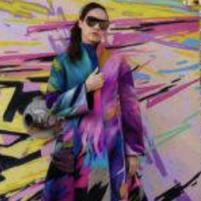 Woman in colorful coat near graffiti wall.