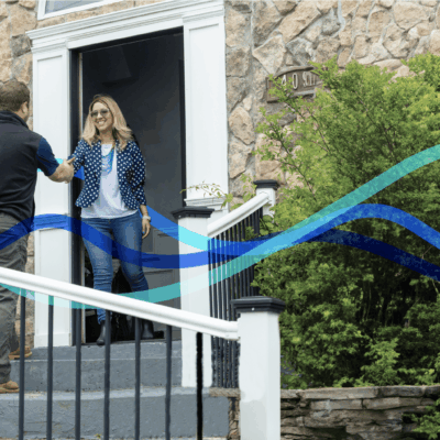 Woman greeting man at front door.