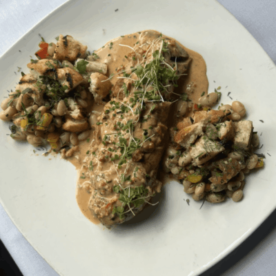 Gourmet dish with sauce and vegetable sides.