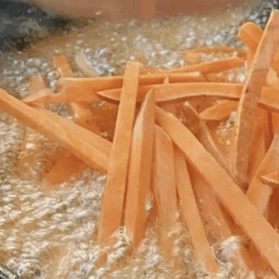 Carrot sticks frying in hot oil.