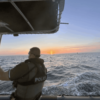 Police officer on boat at sunset.