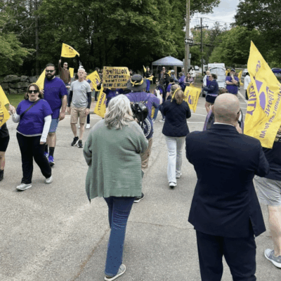 People marching with yellow flags, wearing purple.