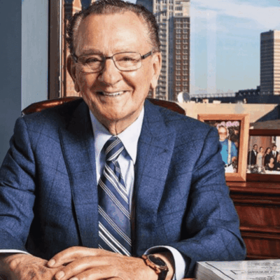 A man in a suit sitting at his desk.