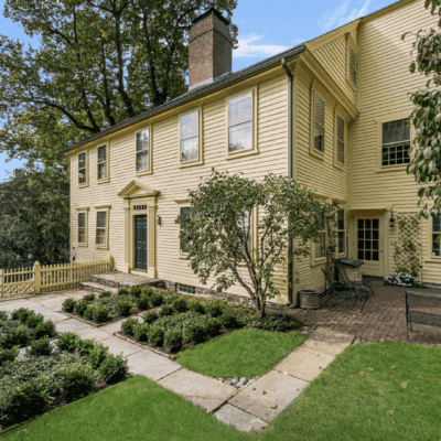 A large yellow house with a garden in the front yard.