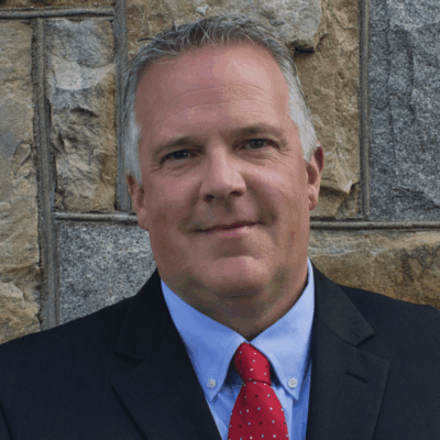 A man in a suit and tie standing next to a wall.