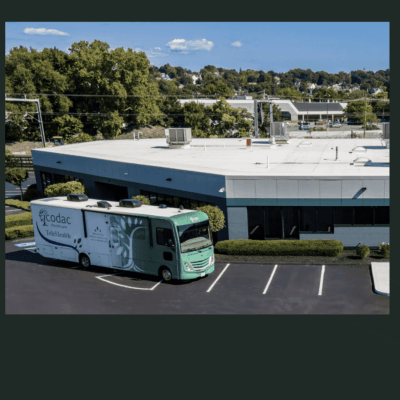 A green and white delivery truck parked outside a commercial building.
