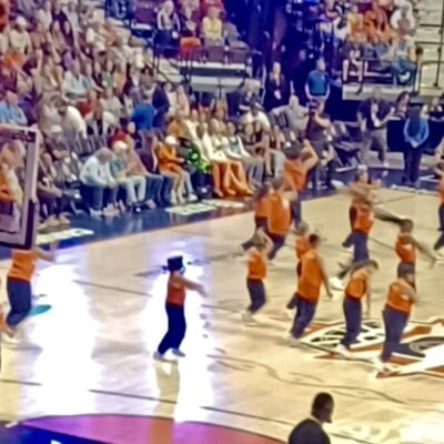 Cheerleaders perform on a basketball court during a game.