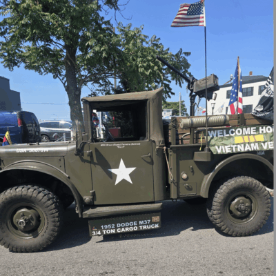 Vintage military truck with American flags and patriotic decor.