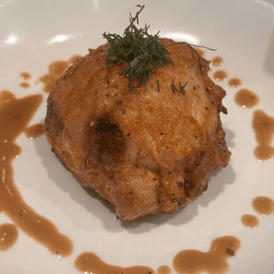 A golden-brown fried ball garnished with herbs and sauce.